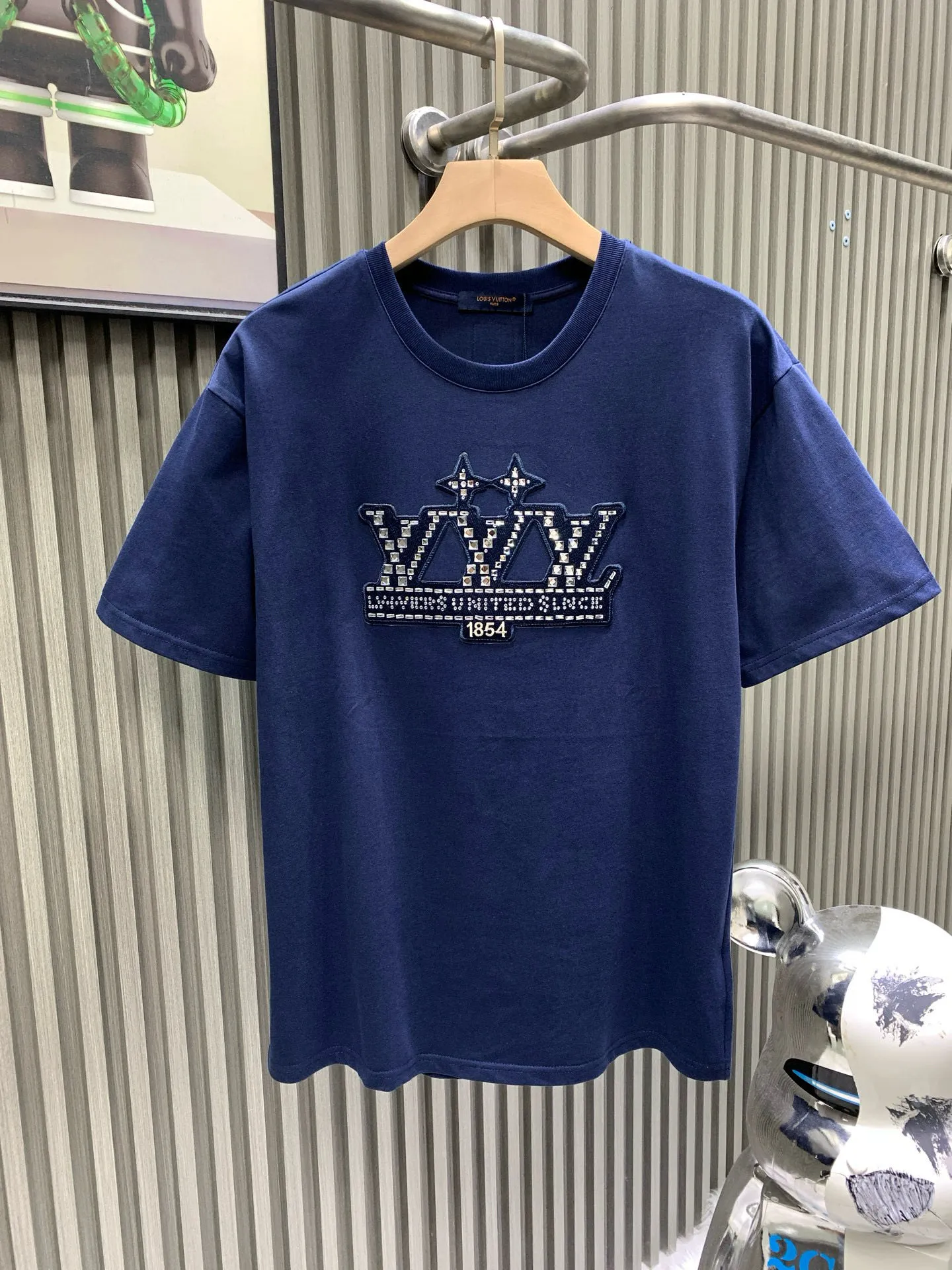 🅿️240 🀄️ Louis Vuitton 1V 2025 new style 1854 diamond letter cotton short sleeves 32-count fine cotton plain fabric is made of combed cotton after a special process. Its fibers are more slender and neat. Therefore, the texture and durability of the fabric are significantly improved. The pure cotton material has excellent moisture absorption. The plain fabric is soft to the touch and comfortable to wear. The fiber structure of combed cotton is tighter. Therefore, the fabric made has better wear resistance and is not easy to pill or deform. The flowers are positioned and embellished with patterns. Diamond selection is to choose diamonds suitable for hot drilling. Diamond arrangement is to arrange the diamonds on the template according to the designed pattern. The diamonds are fixed on the fabric through a hot drilling machine. The color of the back glue should be uniform and consistent, and the firmness should be high. It combines the softness of silicone oil and the high-density characteristics of elastic glue. The material has excellent stretching and recovery properties and can quickly return to its original shape when subjected to external forces to maintain the integrity and clarity of the pattern.